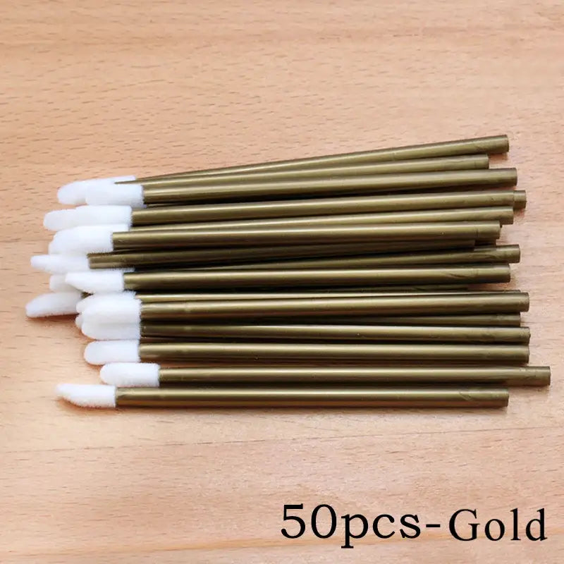 Gold-colored lip gloss applicators with white tips.