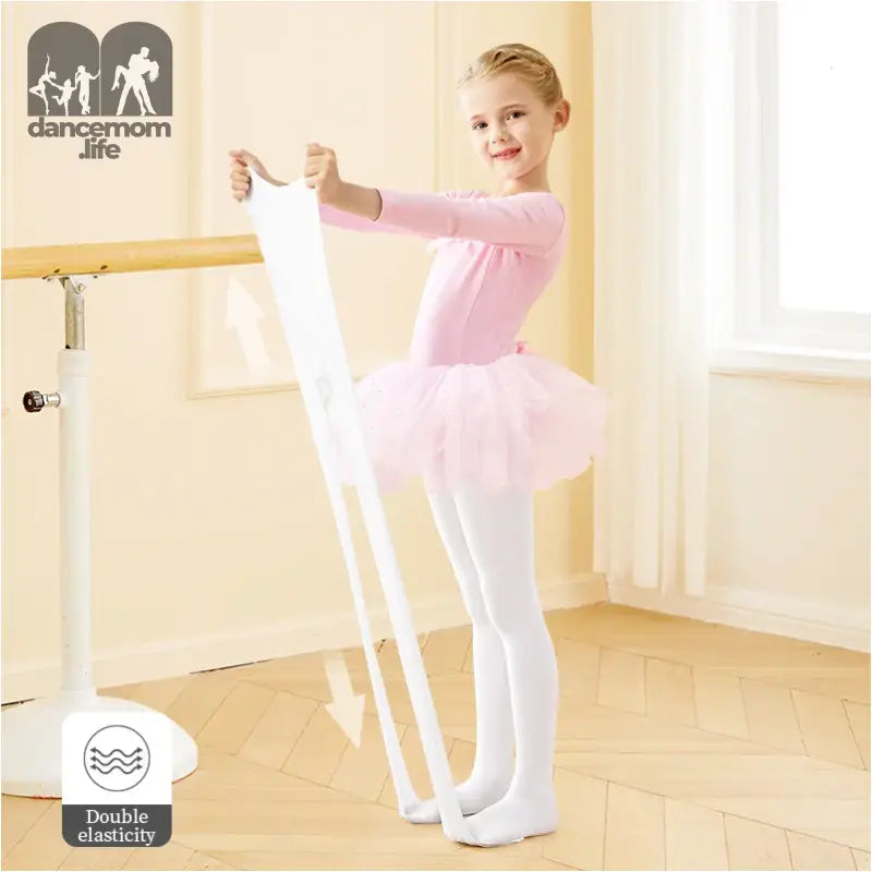 Young ballet dancer in a pink tutu and white tights practicing at a ballet barre.