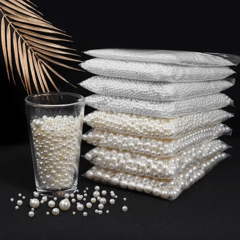 Stacks of white pearl beads in clear plastic bags with some loose pearls and a glass containing pearls.