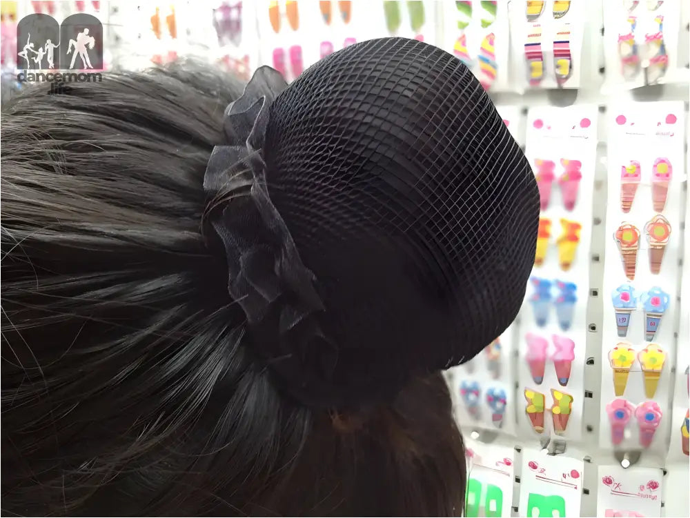 Black knit hair bun cover with a ruffled fabric accent.