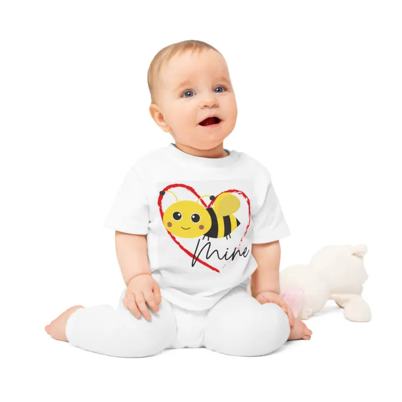 Baby wearing a white outfit with a cute bee heart design.