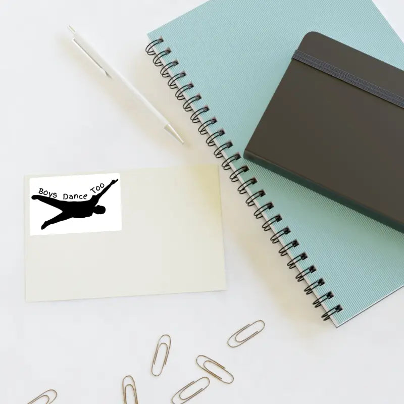 Spiral notebook with a mint green cover alongside paper clips and a black device.