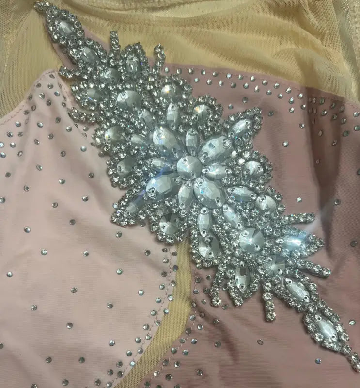 Ornate crystal and rhinestone floral appliqué on pink fabric.