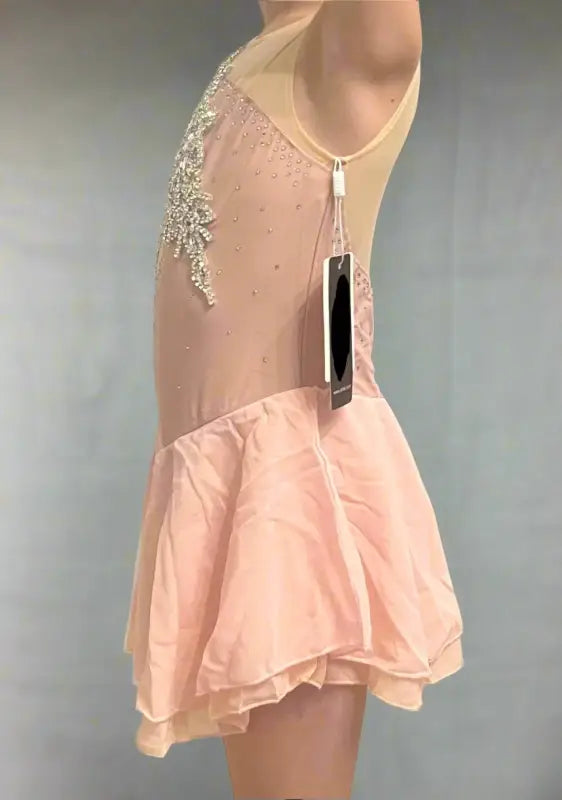 Pale pink figure skating dress with crystal embellishments and a flared skirt.