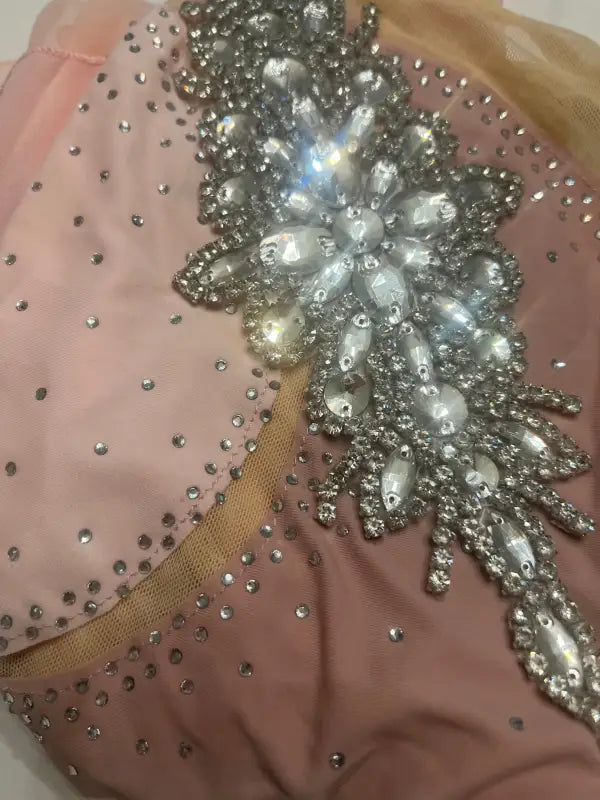 Ornate rhinestone and pearl embellishment on pink fabric.