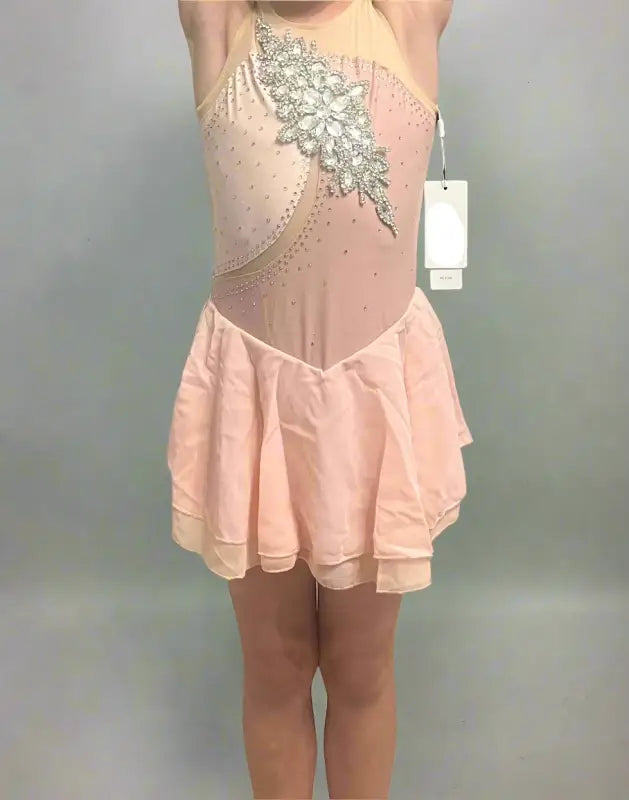 Pale pink figure skating dress with silver embellishments and a short skirt.