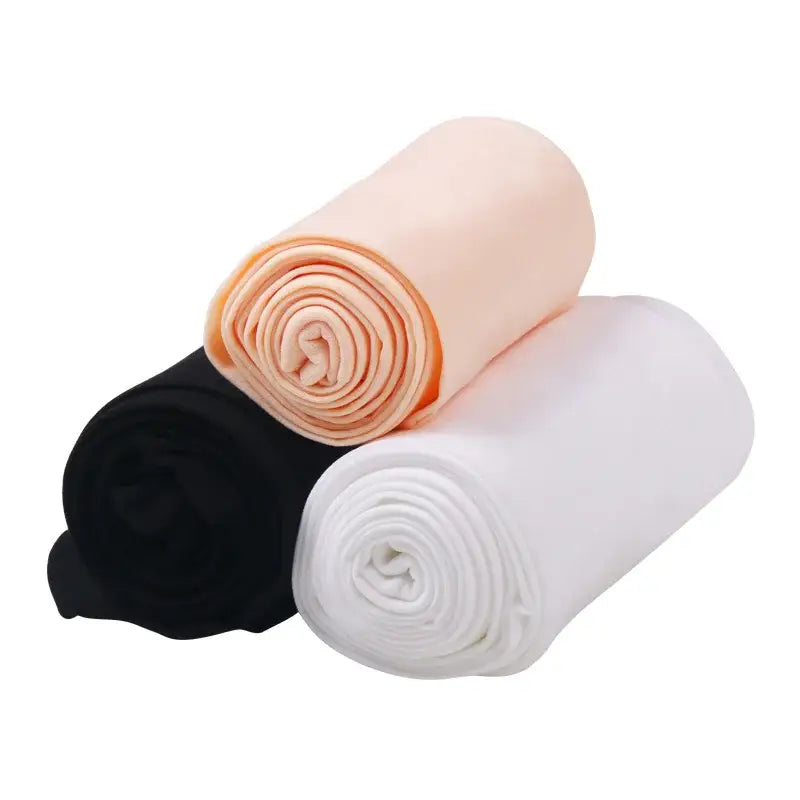 Three rolled-up fabric or textile pieces in peach, black, and white colors.