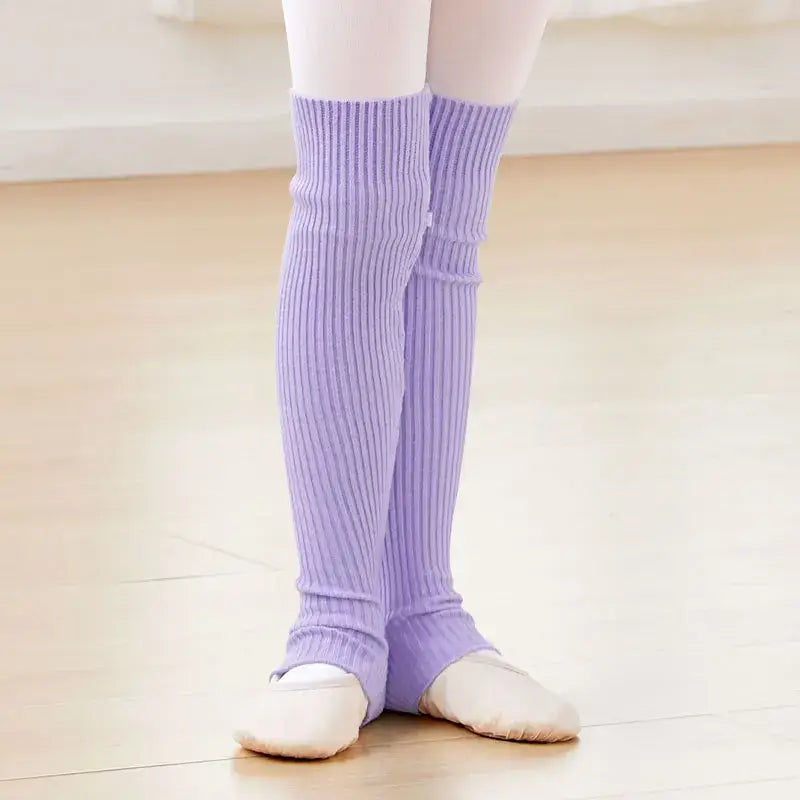 Lavender knit leg warmers worn over white ballet shoes.