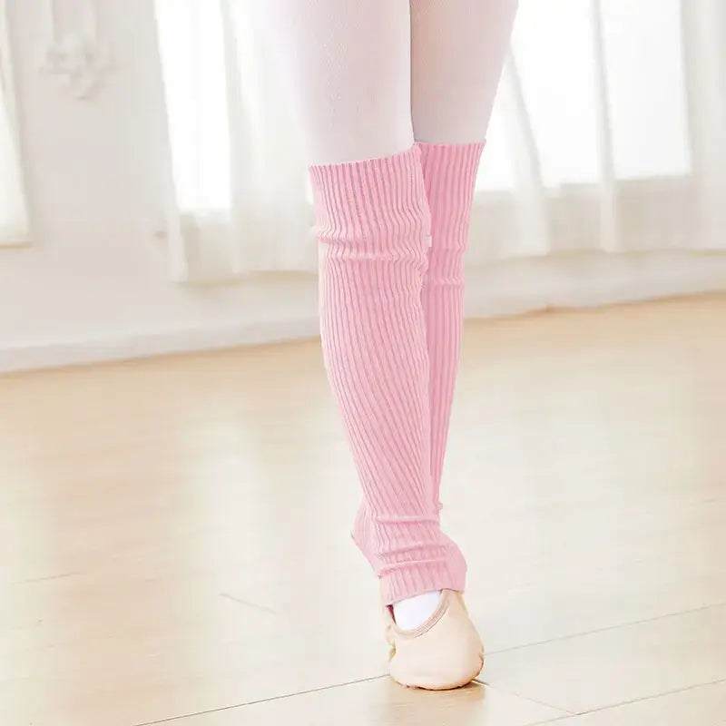 Pink knit leg warmers worn over ballet shoes.