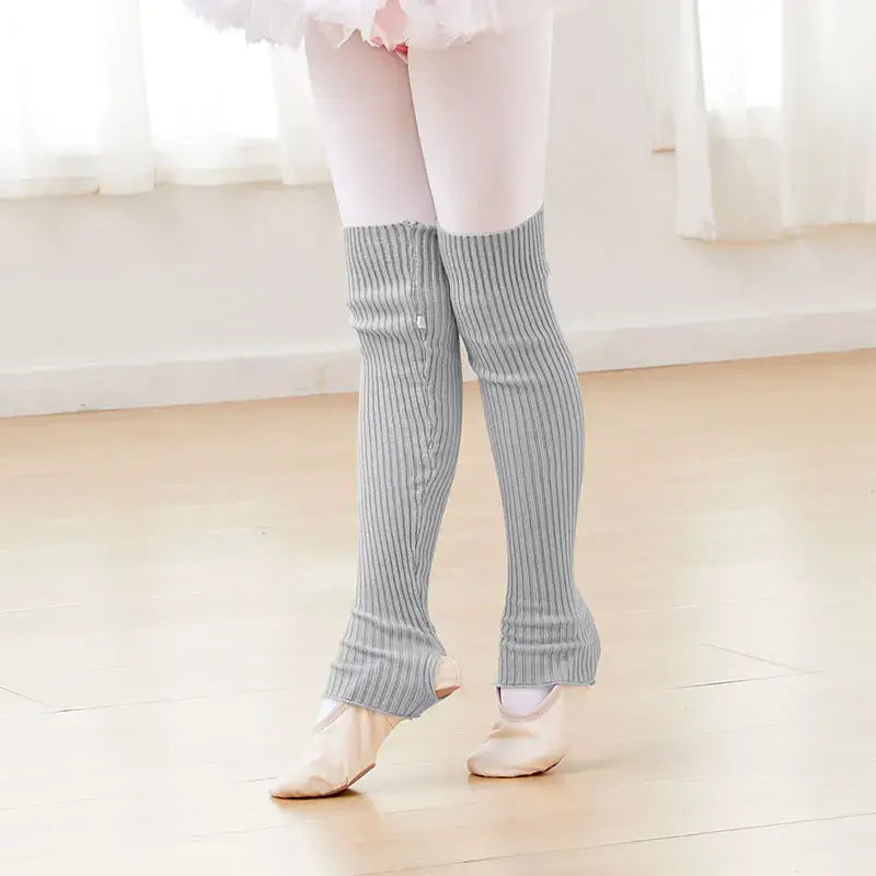 Gray knit leg warmers worn over pink tights with ballet shoes.