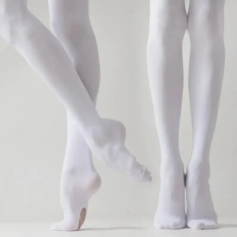 White ballet tights and pointe shoes on dancer’s legs.