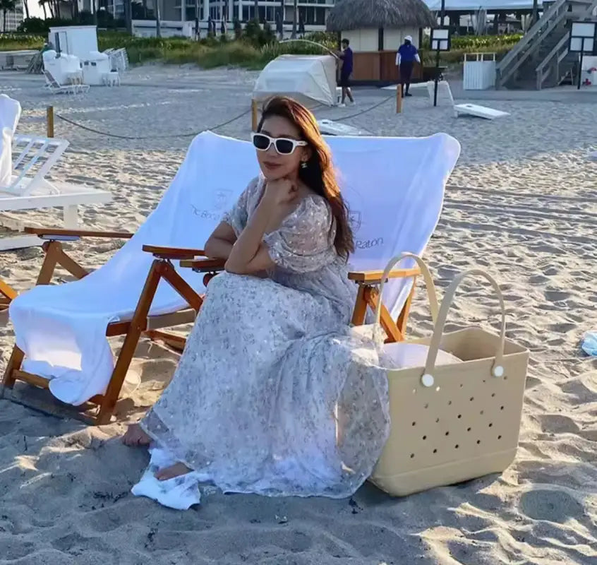 Woman in floral dress sitting on beach chair.