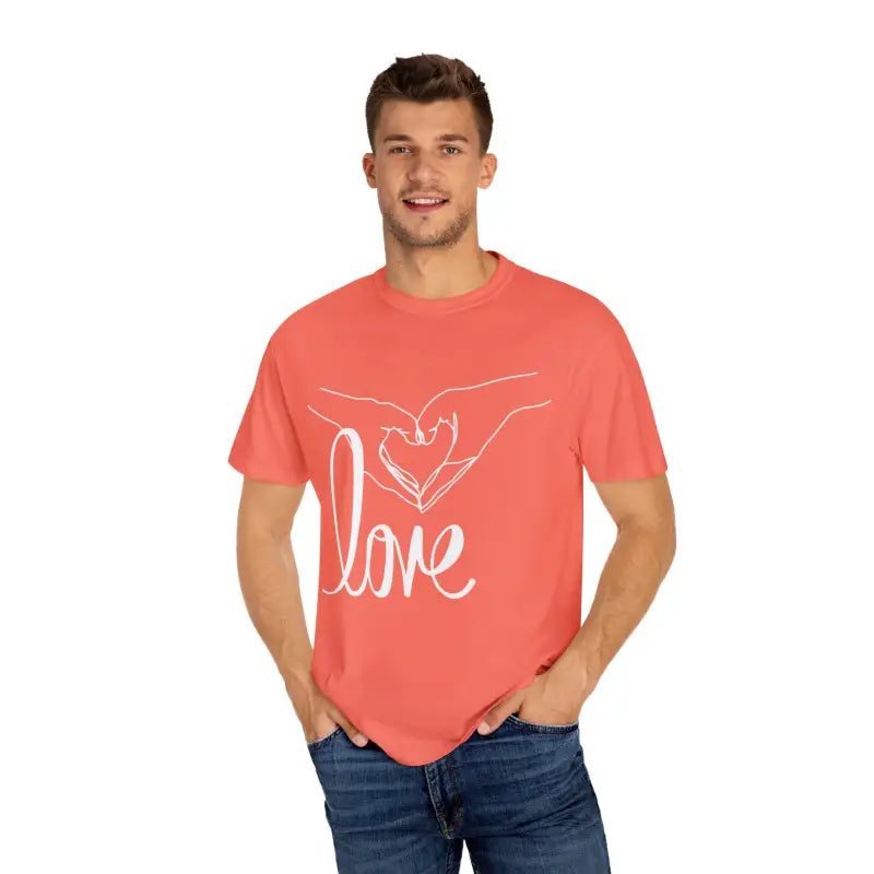 Coral-colored t-shirt with a white ’love’ design featuring hands forming a heart shape.