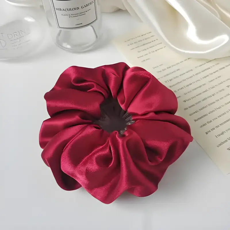 Deep red silk scrunchie with gathered fabric folds.
