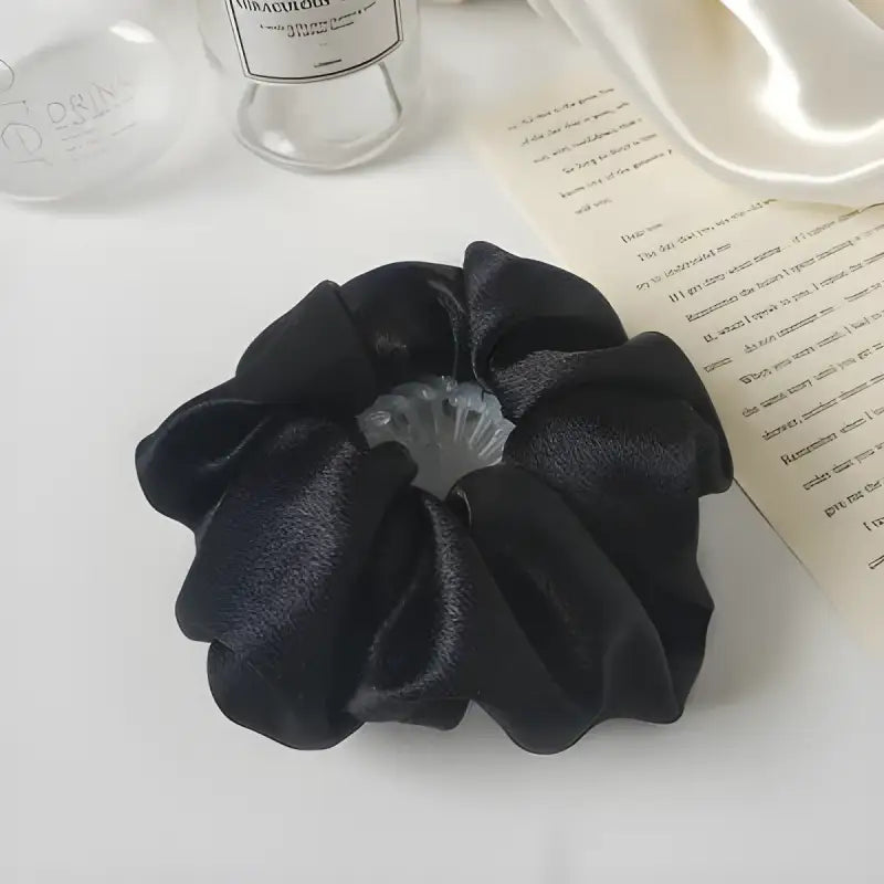 Black satin scrunchie with ruffled fabric design.