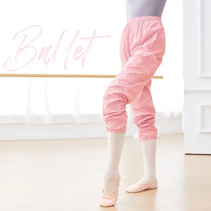 Pink ballet warm-up pants worn over white tights and pink ballet slippers.