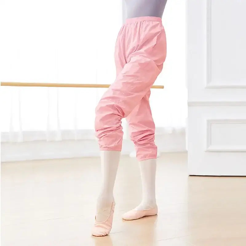 Pink dance warm-up pants with elastic cuffs worn with ballet slippers.