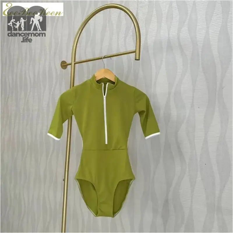 Olive green half-zip bodysuit with white trim and short sleeves hanging on a brass display hook.