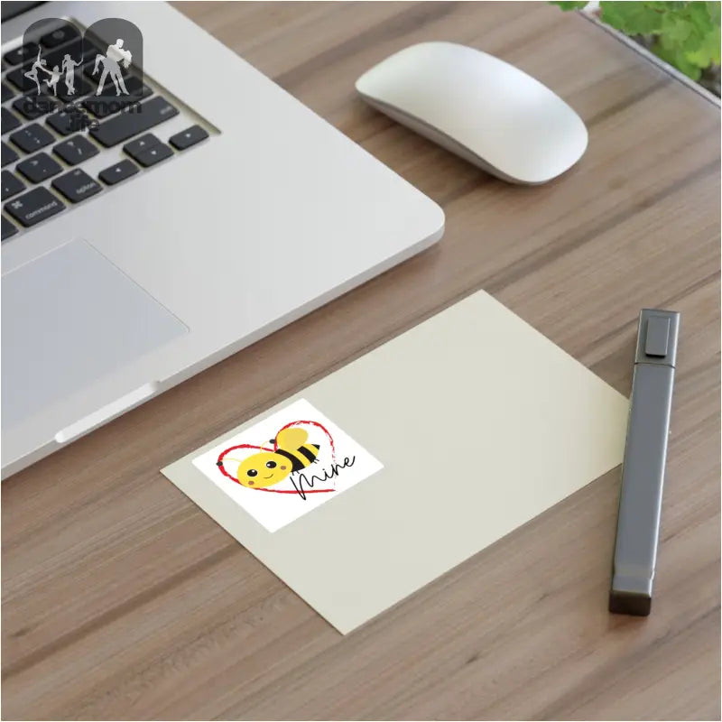 A white laptop with a wireless mouse and notepad on a wooden surface.