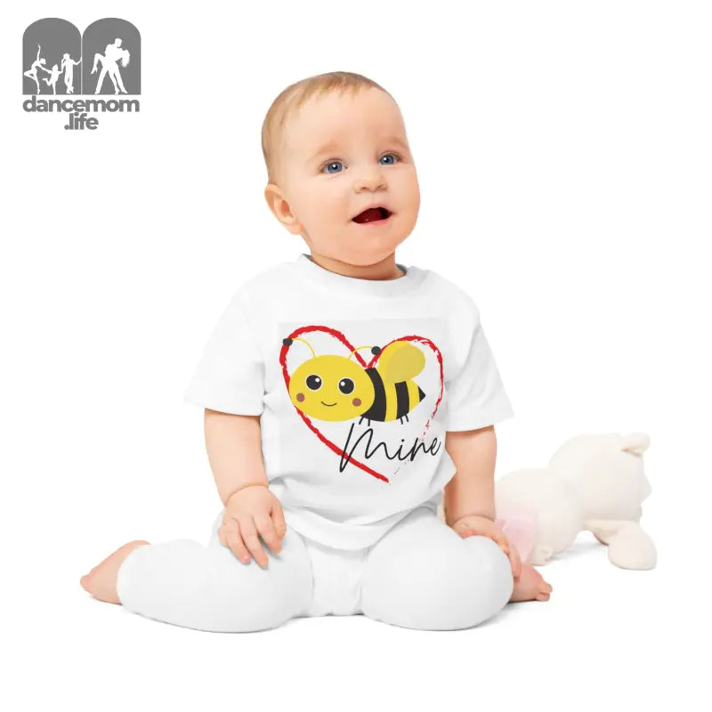 Baby wearing a white outfit with a cute bee heart design.