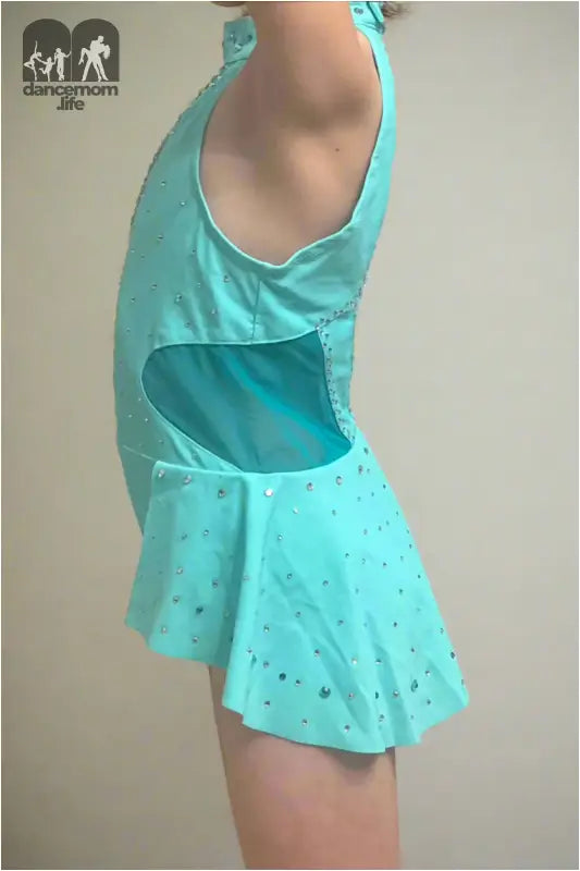 Turquoise figure skating dress with sparkly embellishments and a cutout detail.