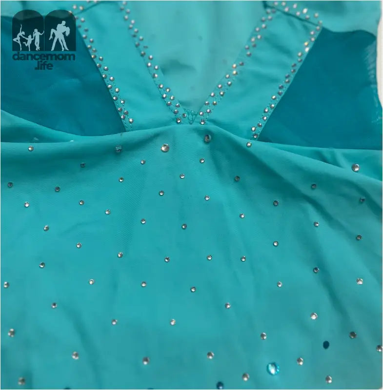 Turquoise fabric adorned with sparkling rhinestones in a V-neck pattern.