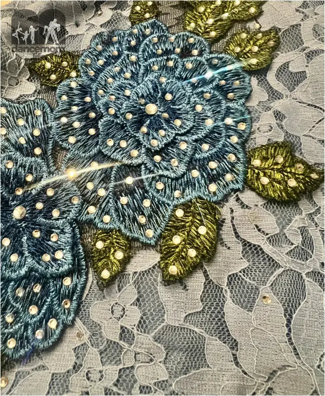 Ornate blue floral embroidery with golden leaves on lace fabric.