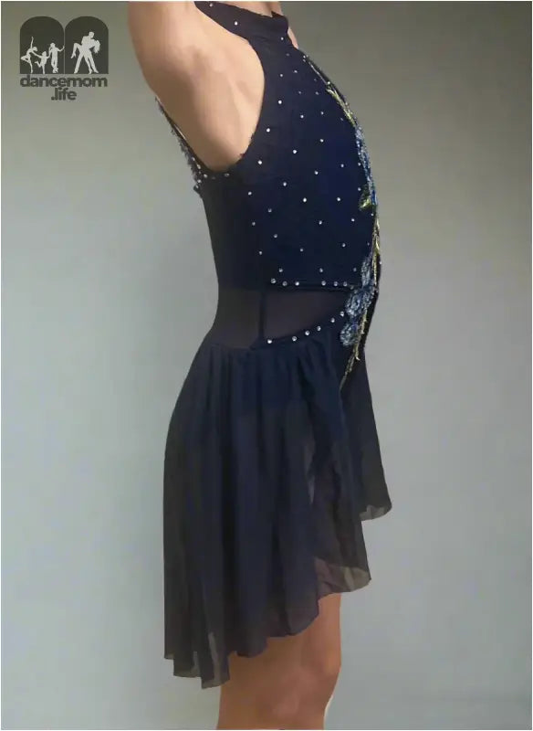 Navy blue figure skating dress with sparkly embellishments and a sheer asymmetrical skirt.