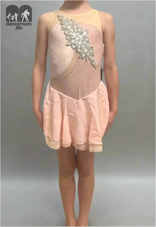 Pale pink figure skating dress with sheer panels and crystal embellishments.