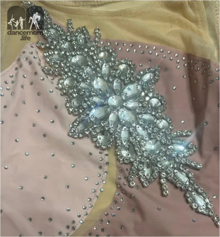 Ornate crystal and rhinestone floral appliqué on pink fabric.