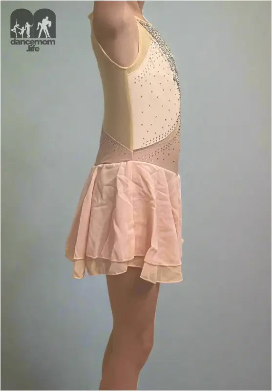 Figure skating dress with a beige bodice and pale pink skirt.