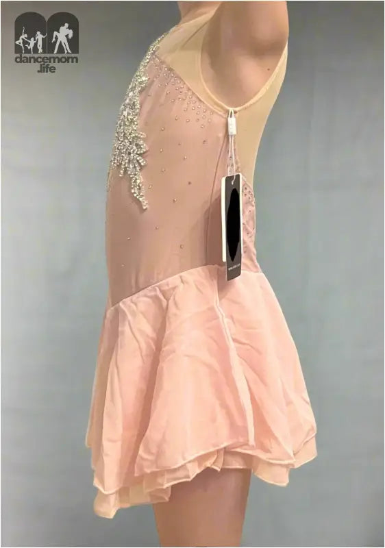 Pale pink figure skating dress with crystal embellishments and a flared skirt.