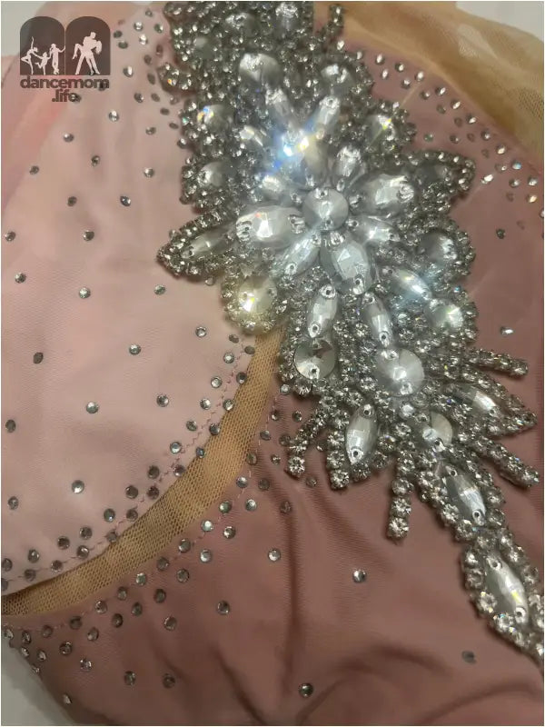 Ornate rhinestone and pearl embellishment on pink fabric.