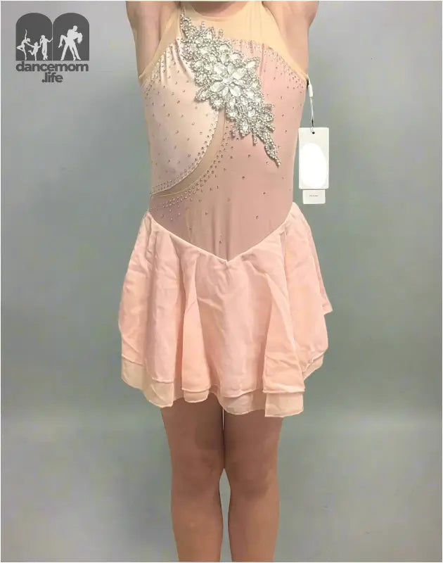 Pale pink figure skating dress with silver embellishments and a short skirt.