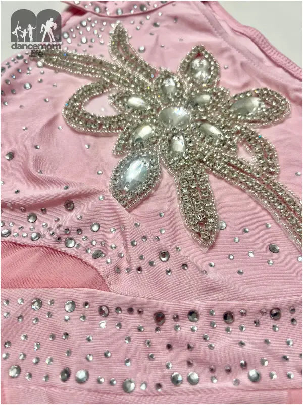 Pink fabric garment adorned with a sparkly silver floral appliqué and scattered rhinestones.