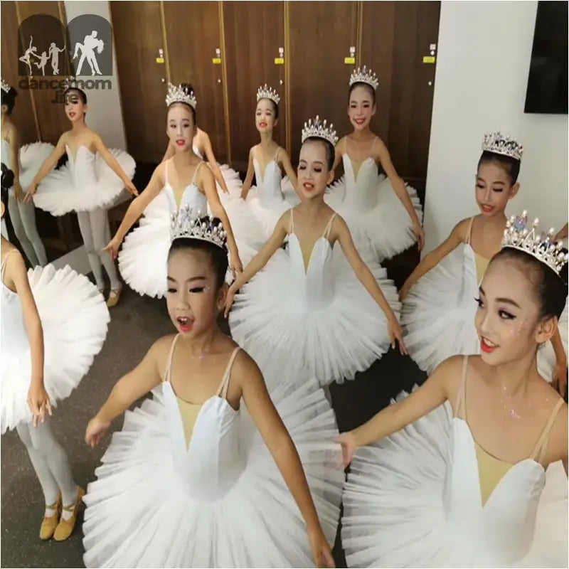 Ballet dancers in white tutus and tiaras performing together.