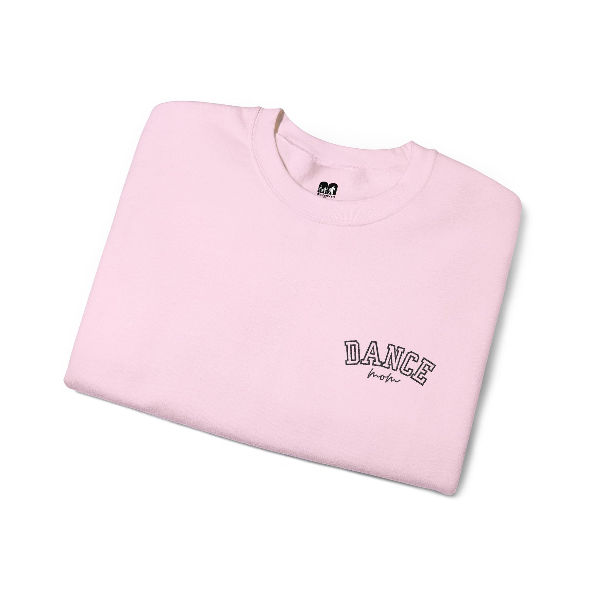 A soft pink crewneck sweatshirt with ’dance’ embroidered in black arched lettering above the word ’mom’ in a cursive script.