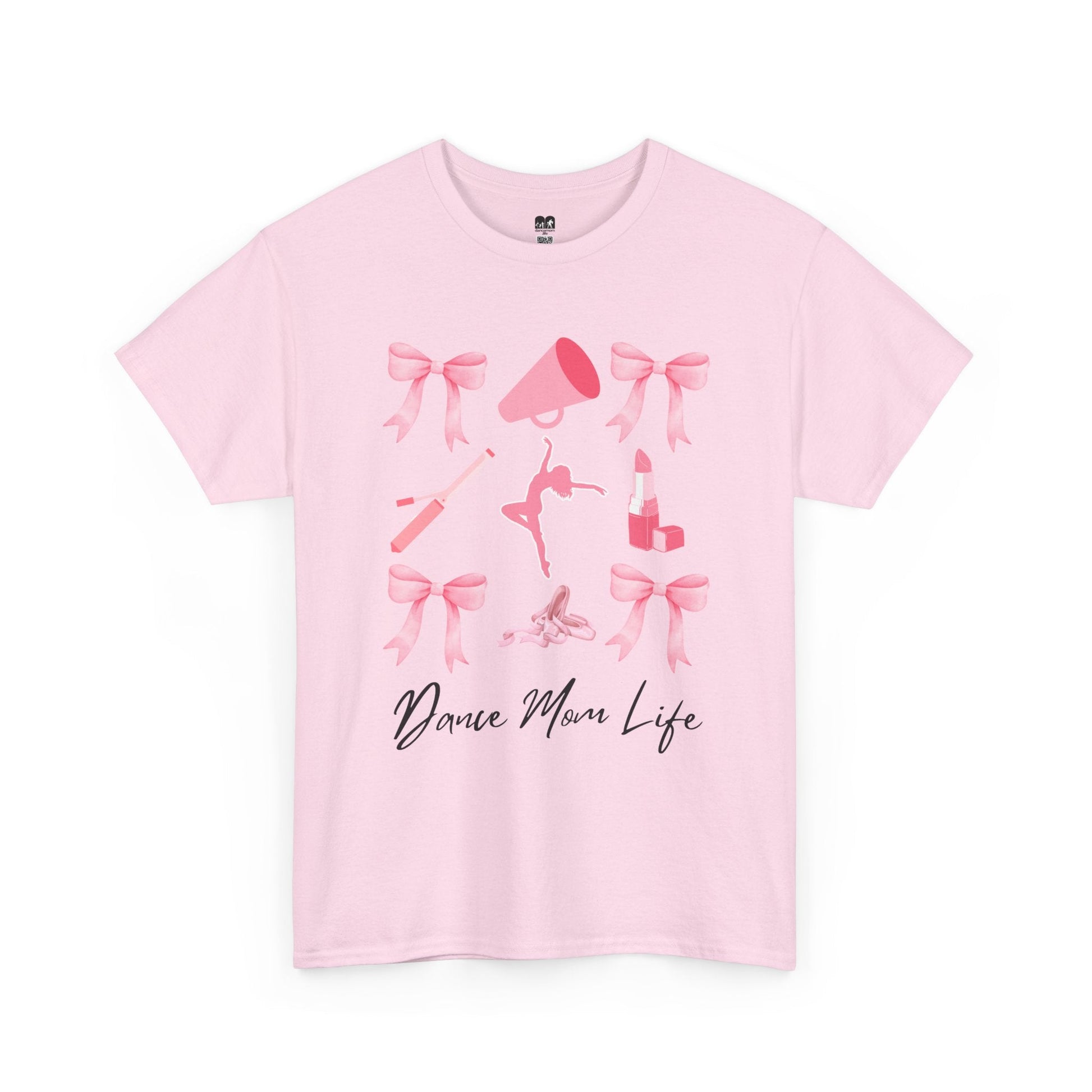 A soft pink cotton t-shirt featuring a playful graphic of bows, a megaphone, ballet shoes, and lipstick with the text ’dance mom life’ printed in black cursive script.