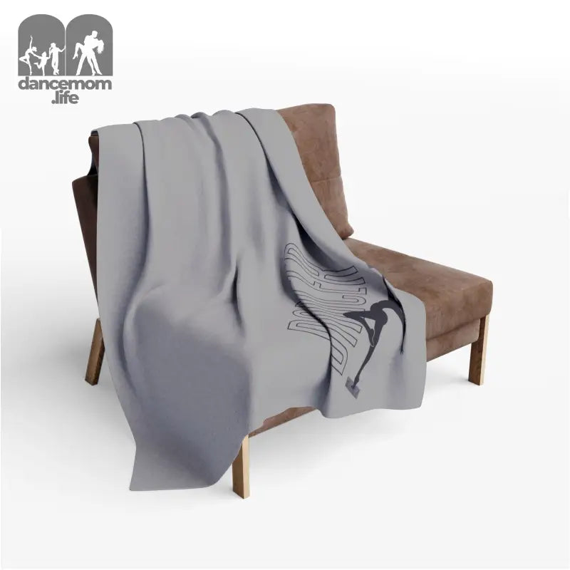 Gray throw blanket with a butterfly design draped over a brown chair.