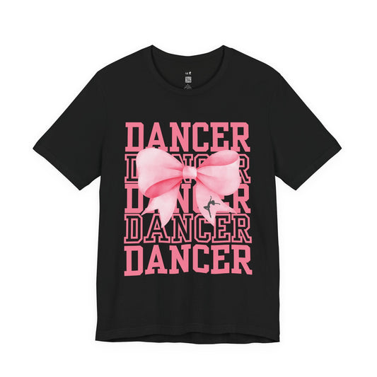 Black cotton t-shirt featuring a bold pink ’dancer’ graphic with layered text and a large, stylized pink bow centered on the front.