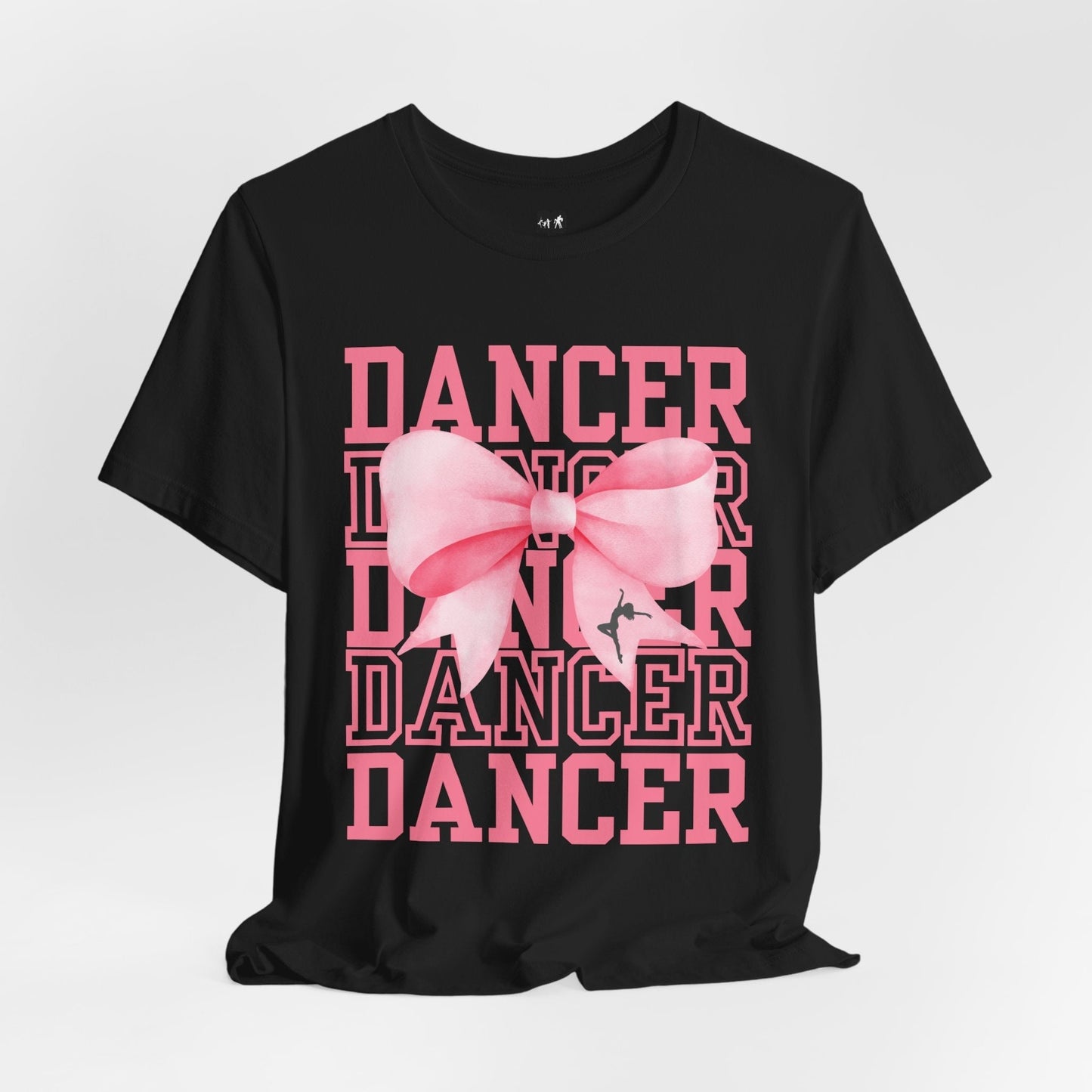 Black cotton t-shirt featuring a bold pink ’dancer’ graphic with layered text and a large, soft-looking pink bow centered over the design.