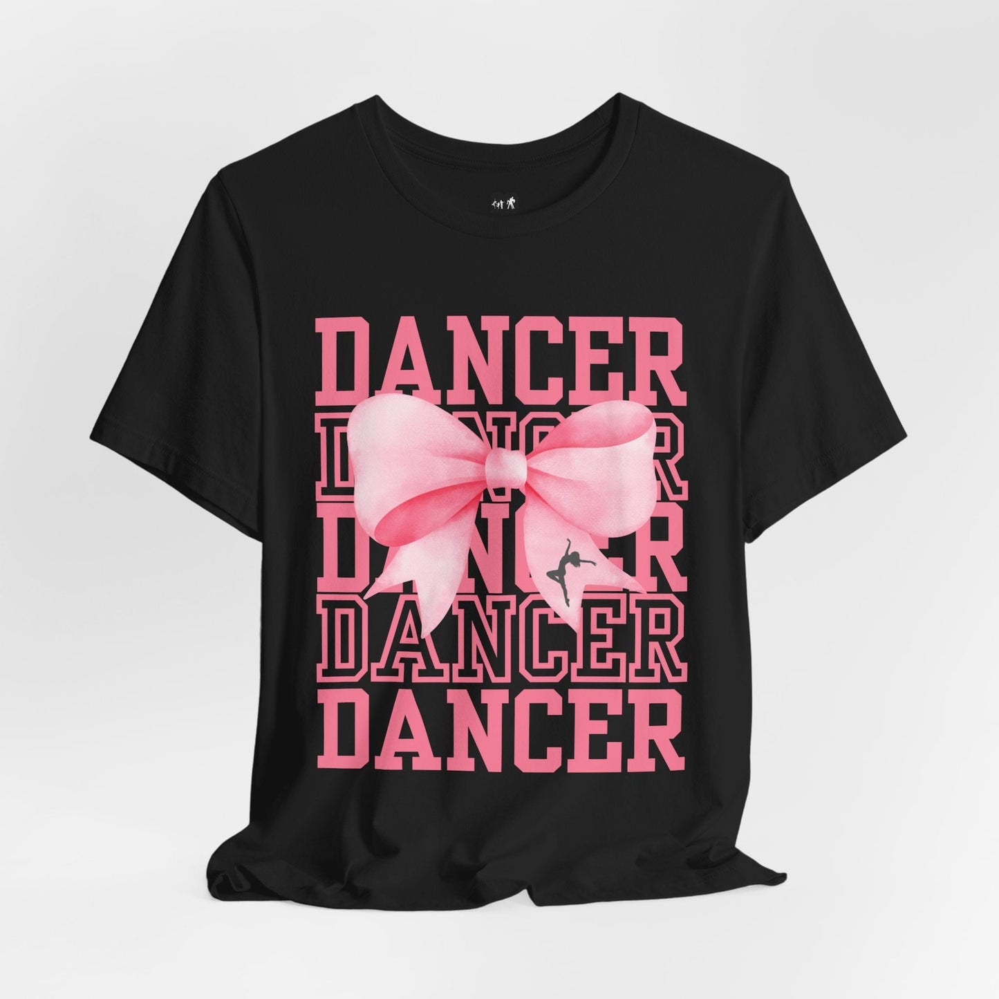 Black cotton t-shirt featuring a bold pink ’dancer’ graphic with layered text and a large, soft-looking pink bow centered over the design.