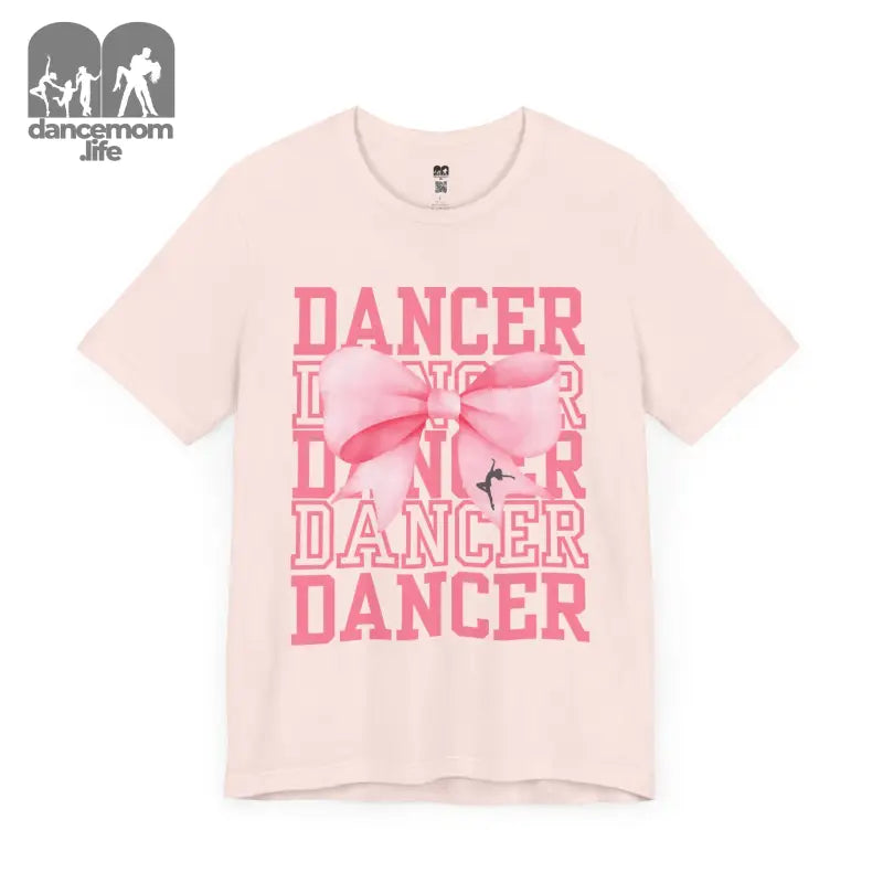 Light pink t-shirt with ’DANCER’ text repeated in pink lettering and a bow design.
