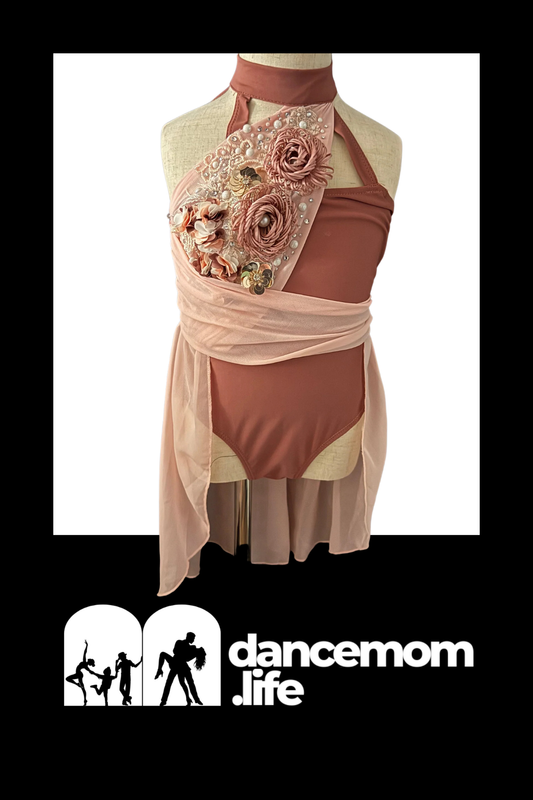 A blush pink dance leotard with a halter neckline, adorned with layered fabric roses and beaded embellishments.
