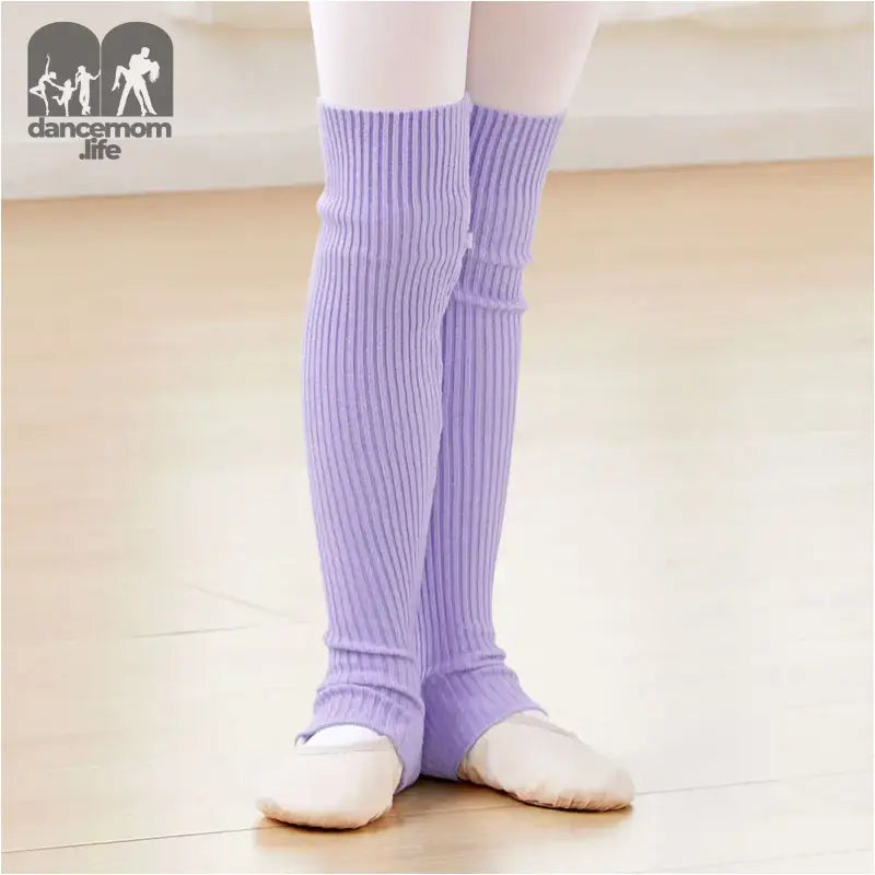 Lavender knit leg warmers worn over white ballet shoes.