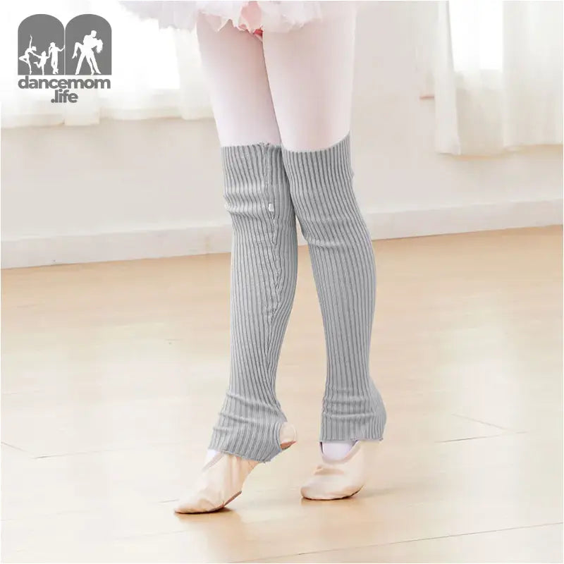 Gray knit leg warmers worn over pink tights with ballet shoes.