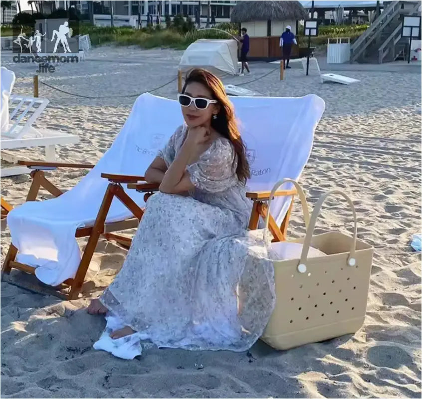 Woman in floral dress sitting on beach chair.