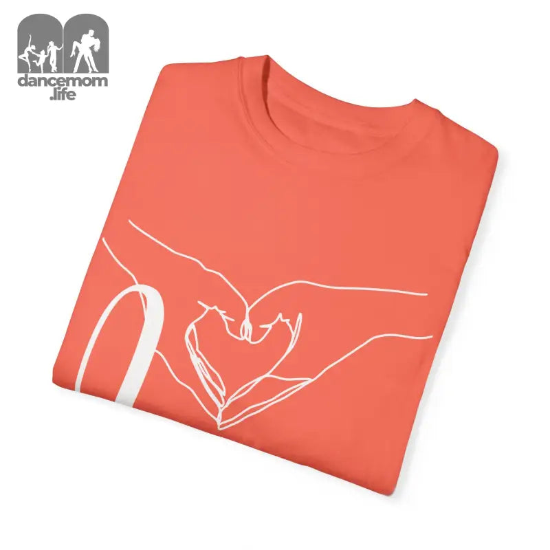 Coral-colored t-shirt with a white line drawing of hands forming a heart shape.