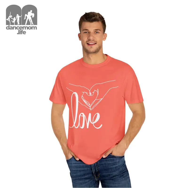 Coral-colored t-shirt with a white ’love’ design featuring hands forming a heart shape.