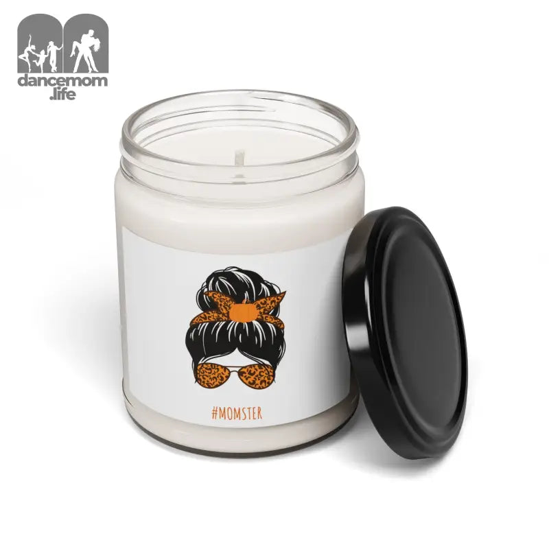 White candle in a glass jar with a black lid and an illustration of a messy bun hairstyle with sunglasses and orange bandana on the label.